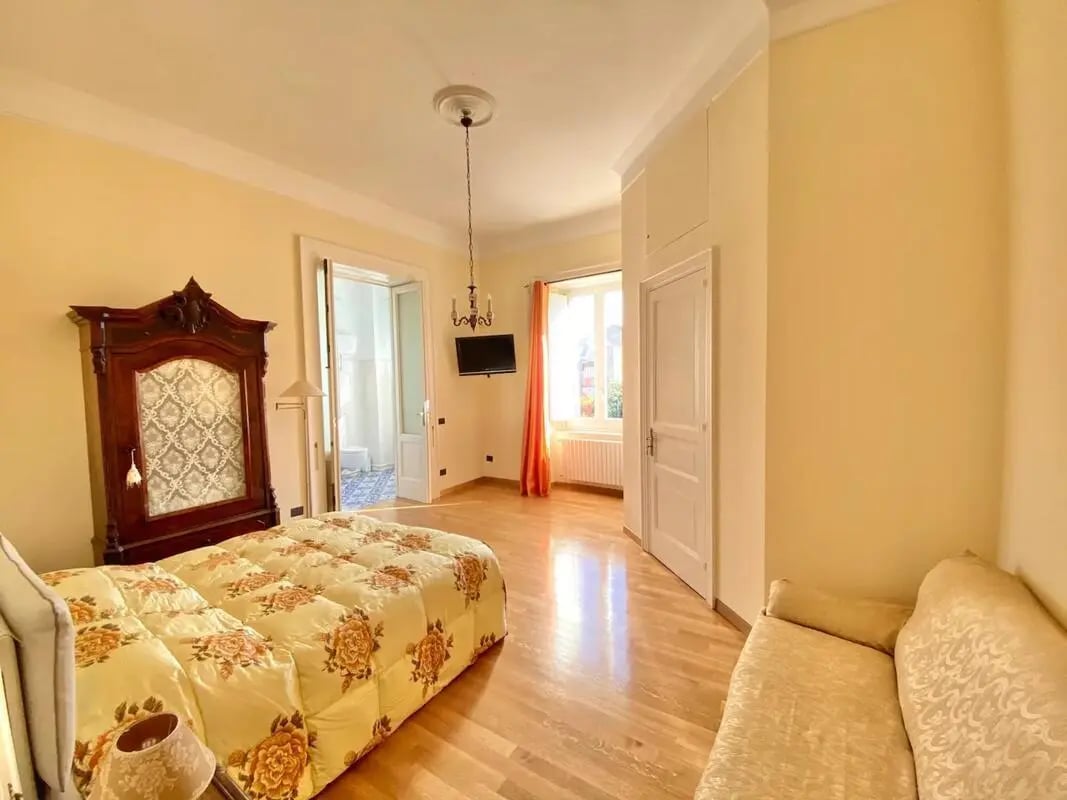 Bedroom with antique wardrobe, floral bedding, sofa, and chandelier bedroom at Appartamento di due stanze in Sant'Agnello Student Accommodation