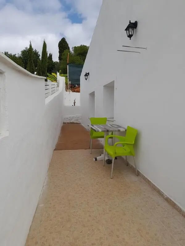 Outdoor table and chairs with greenery Exterior at Enjoyable 1-bedroom flat within walking distance of the beaches in Albufeira Student Accommodation