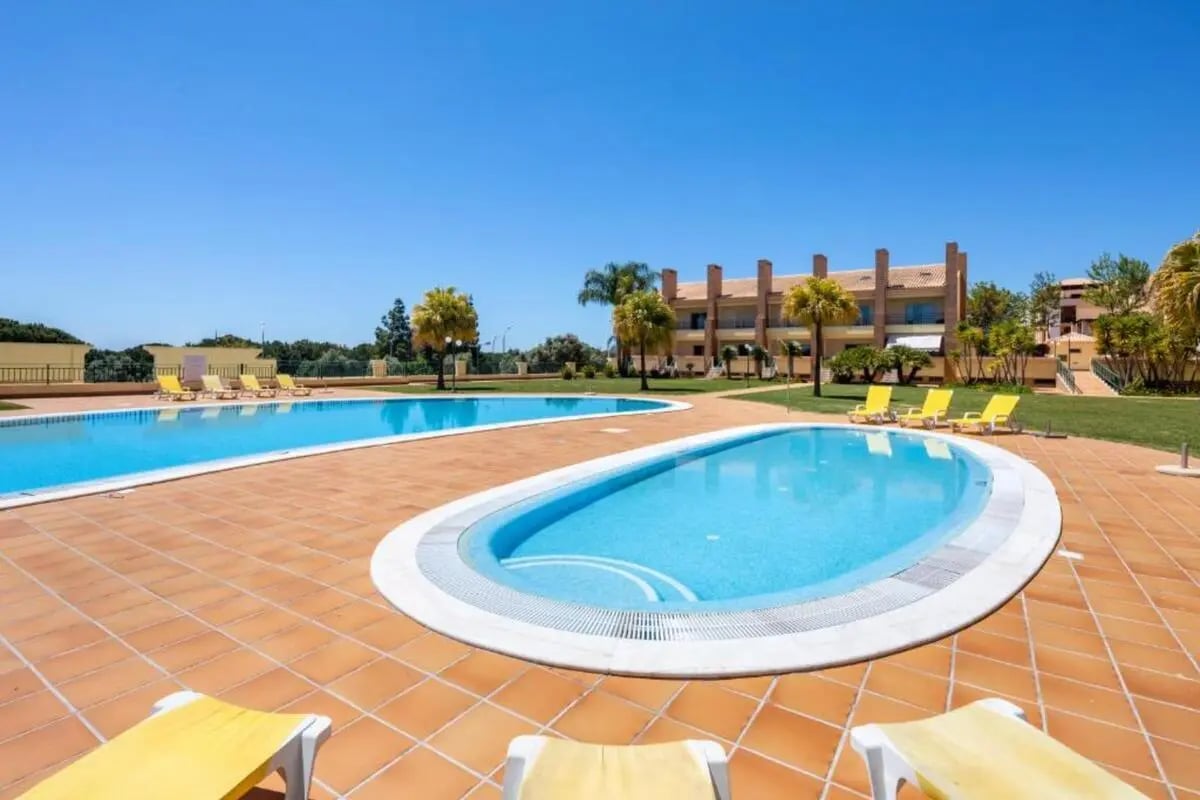 Two pools yellow loungers building exterior at Welcoming 1-bedroom apartment with swimming pool access in Vilamoura in Vilamoura Student Accommodation