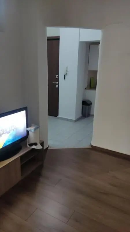 Television on stand doorway leads to kitchen living room at Nice double private bedroom, near to Aristotle University of Thessaloniki in Thessaloniki Student Accommodation