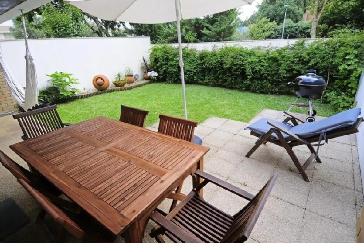 Wooden table chairs hammock grill patio area outdoor area at Modern 3 Bedroom House close to Polytechnic Institute of Cávado and Ave (IPCA) in Póvoa De Varzim Student Accommodation