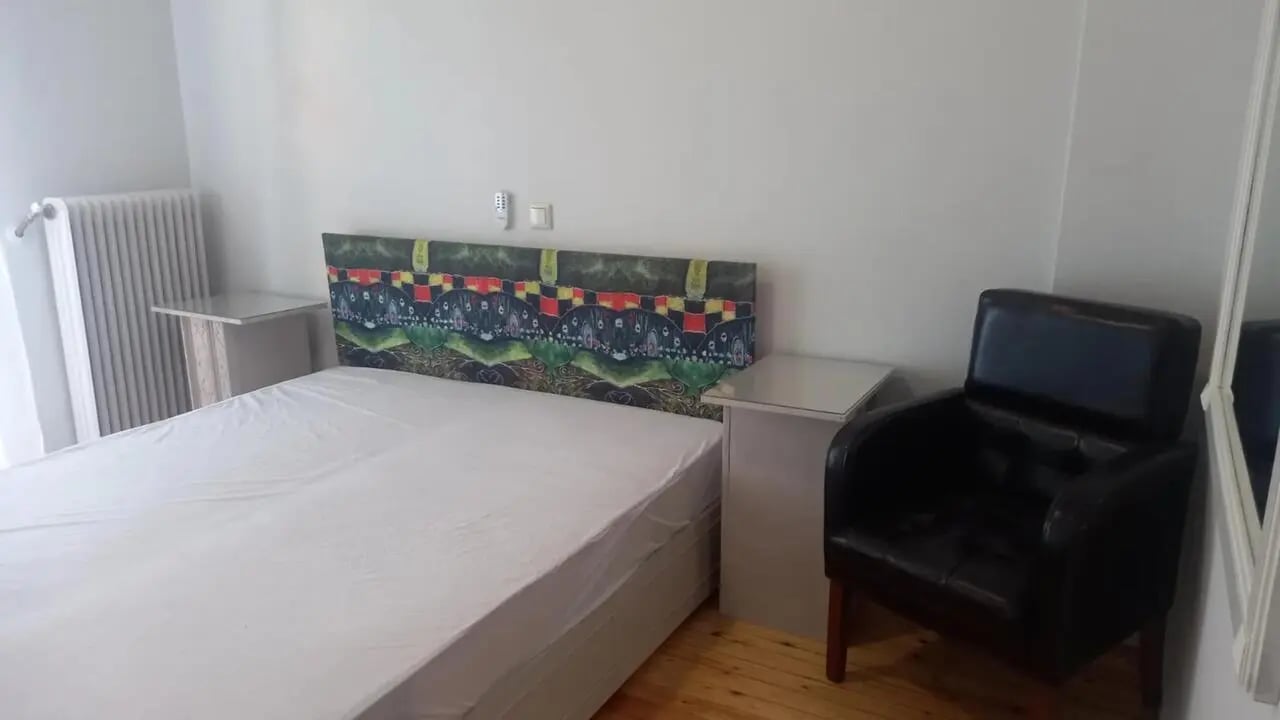 Bed nightstands chair and radiator bedroom at Spacious four bedroom apartment near the University of Thessaloniki in Thessaloniki Student Accommodation