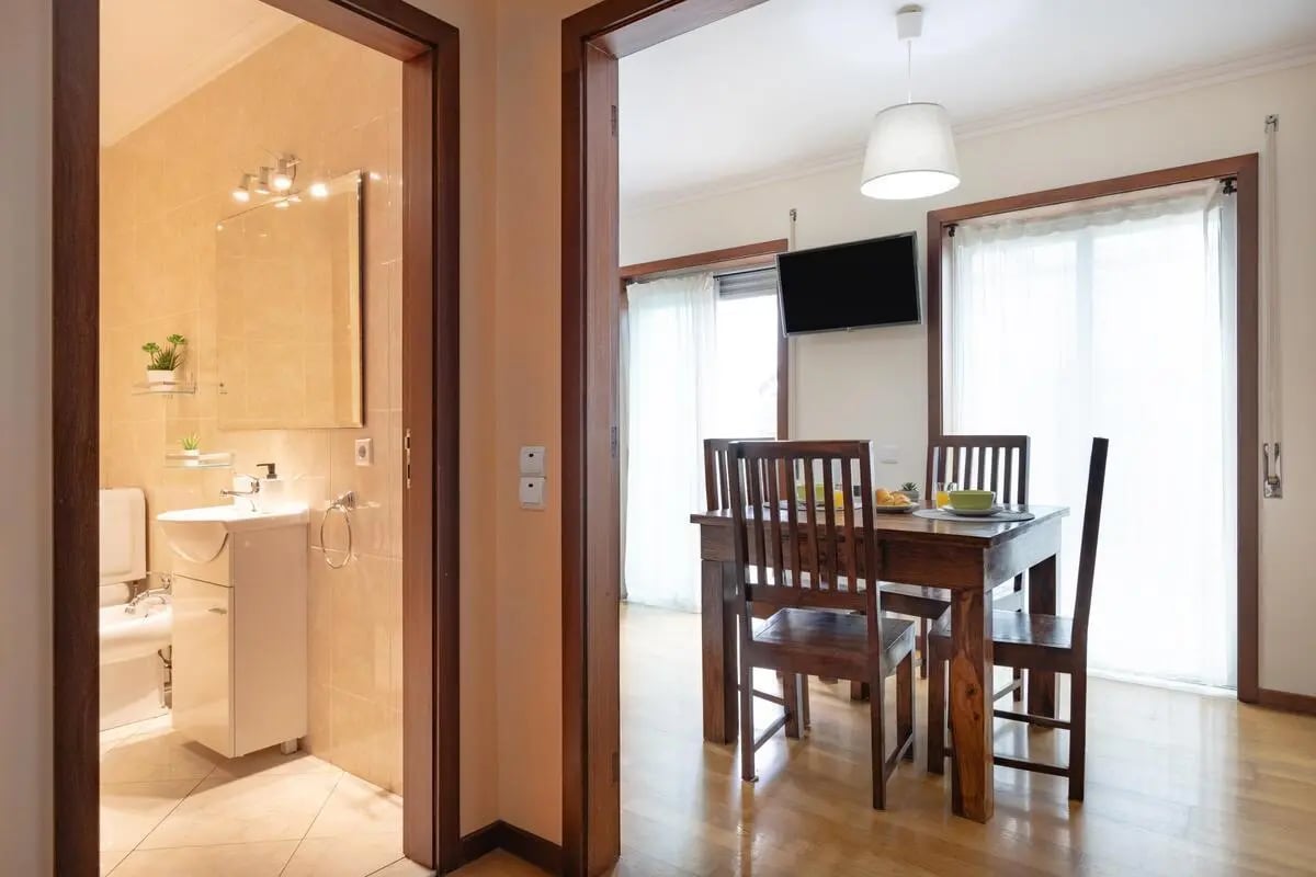 Bathroom with sink and toilet dining table with chairs living room at Comfortable 2-bedroom flat in Espinho in Espinho Student Accommodation