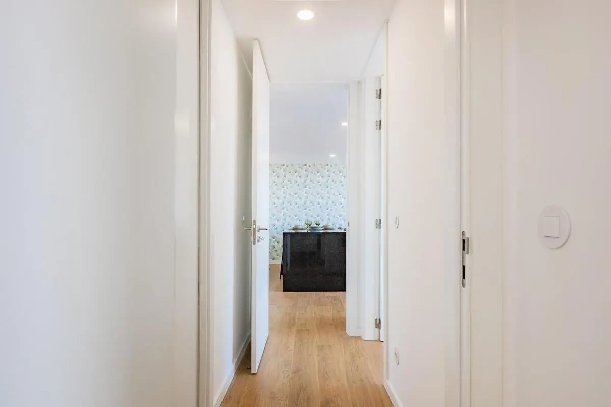 White hallway with open doors looking into kitchen at Bright 2-bedroom flat in Espinho in Espinho Student Accommodation