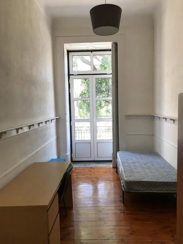 Single bed desk chair and French doors bedroom at Sunny single bedroom in Covilha Student Accommodation
