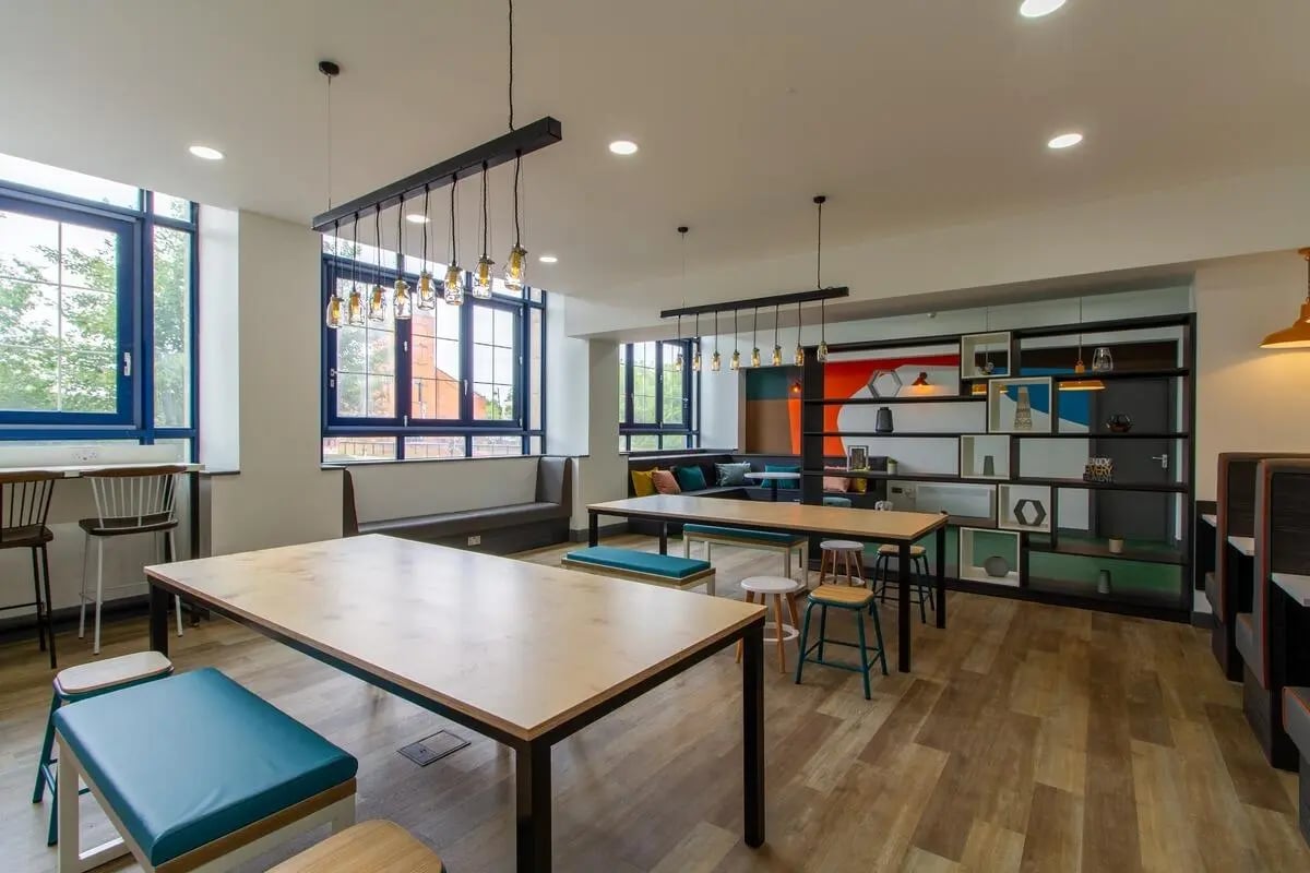 Dining tables benches and shelving unit communal area at Ben Russell Court in Leicester Student Accommodation