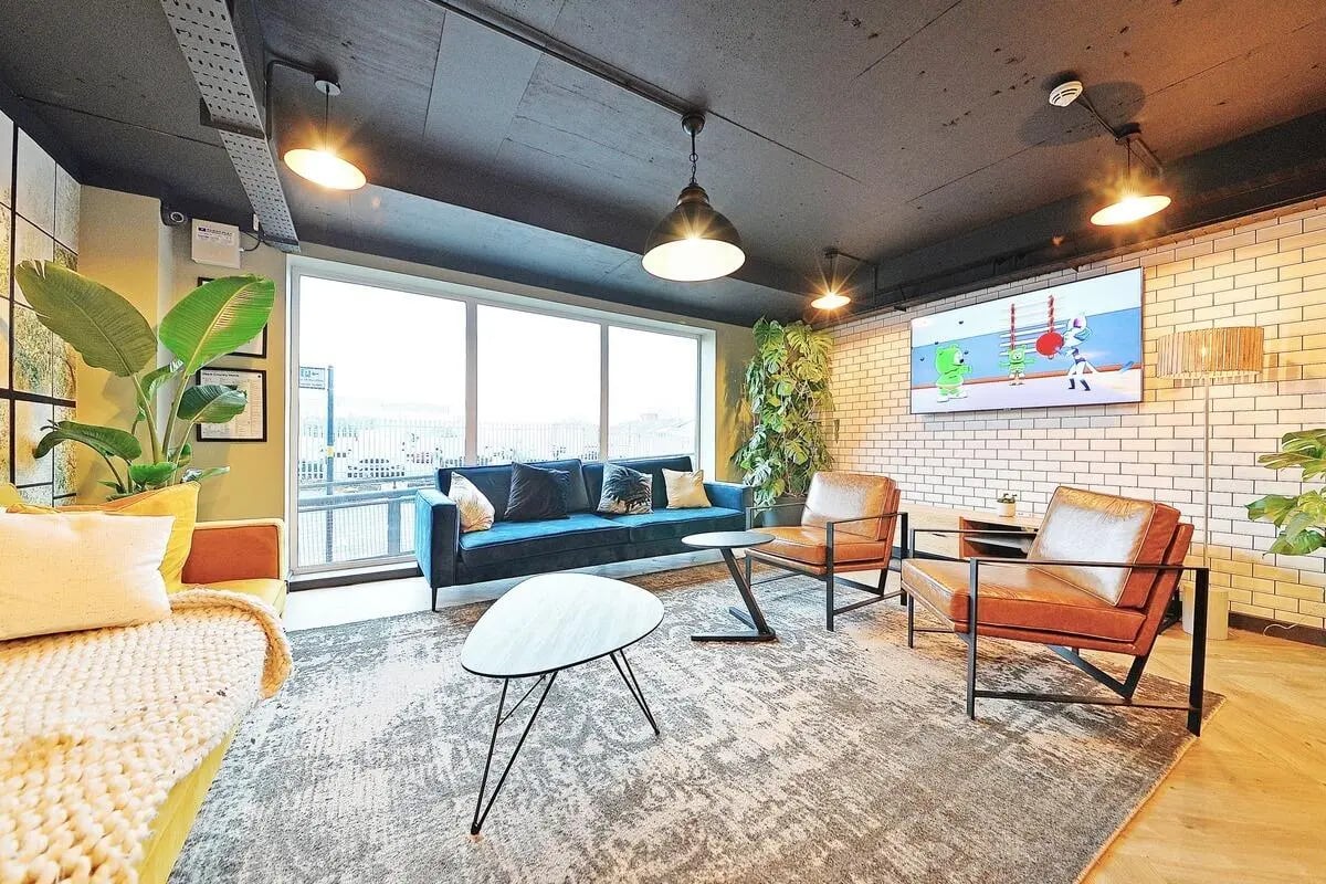 Blue sofa armchairs coffee tables televisions living room at Canalside in Birmingham Student Accommodation