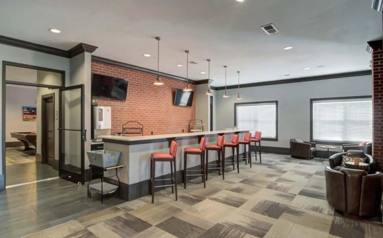 Bar with red stools and pool table visible living room at The Flats At Carrs Hill in Athens Student Accommodation