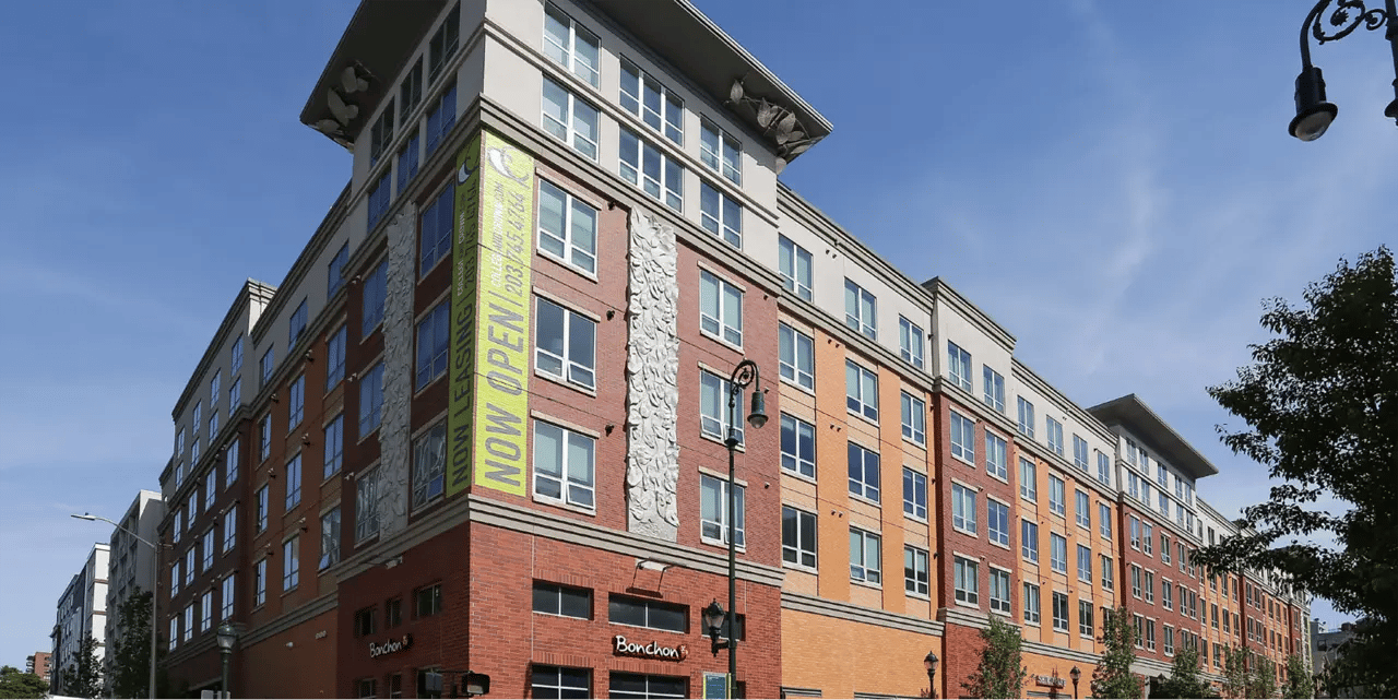 Modern building with NOW OPEN banner exterior at College and Crown Apartments in New Haven Student Accommodation