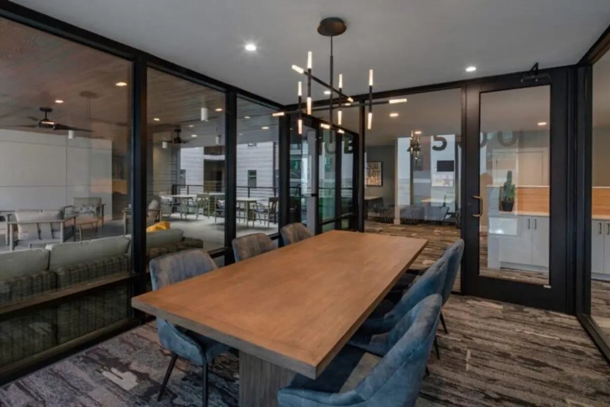 Wood table and chairs with modern chandelier common area at Noble 2500 in Austin Student Accommodation