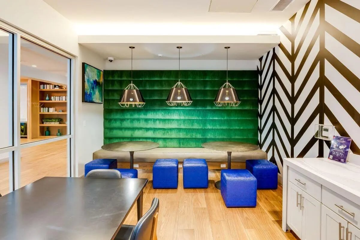 Green wall seating with blue ottomans and tables common area at The Crossings Apartments in Sacramento Student Accommodation