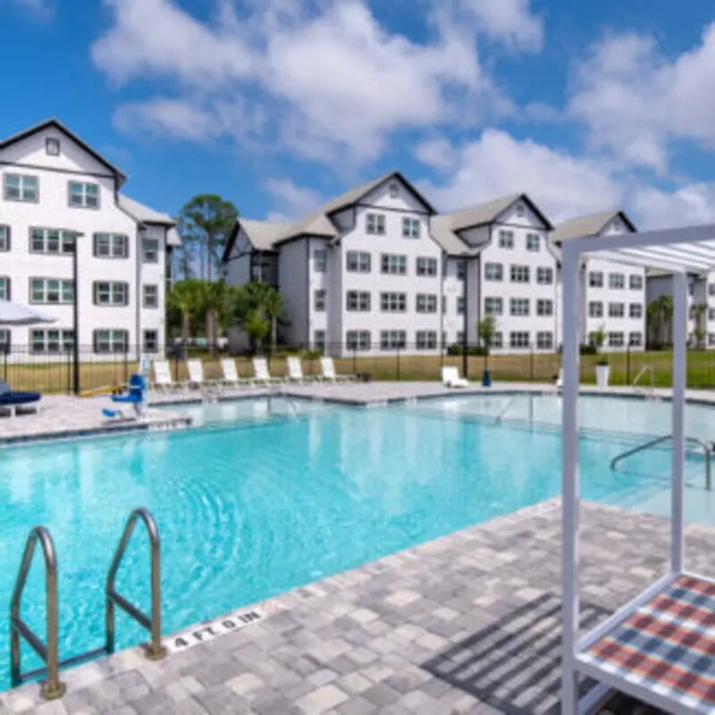 Pool with lounge chairs and buildings exterior at Bellamy Daytona in Daytona Beach Student Accommodation