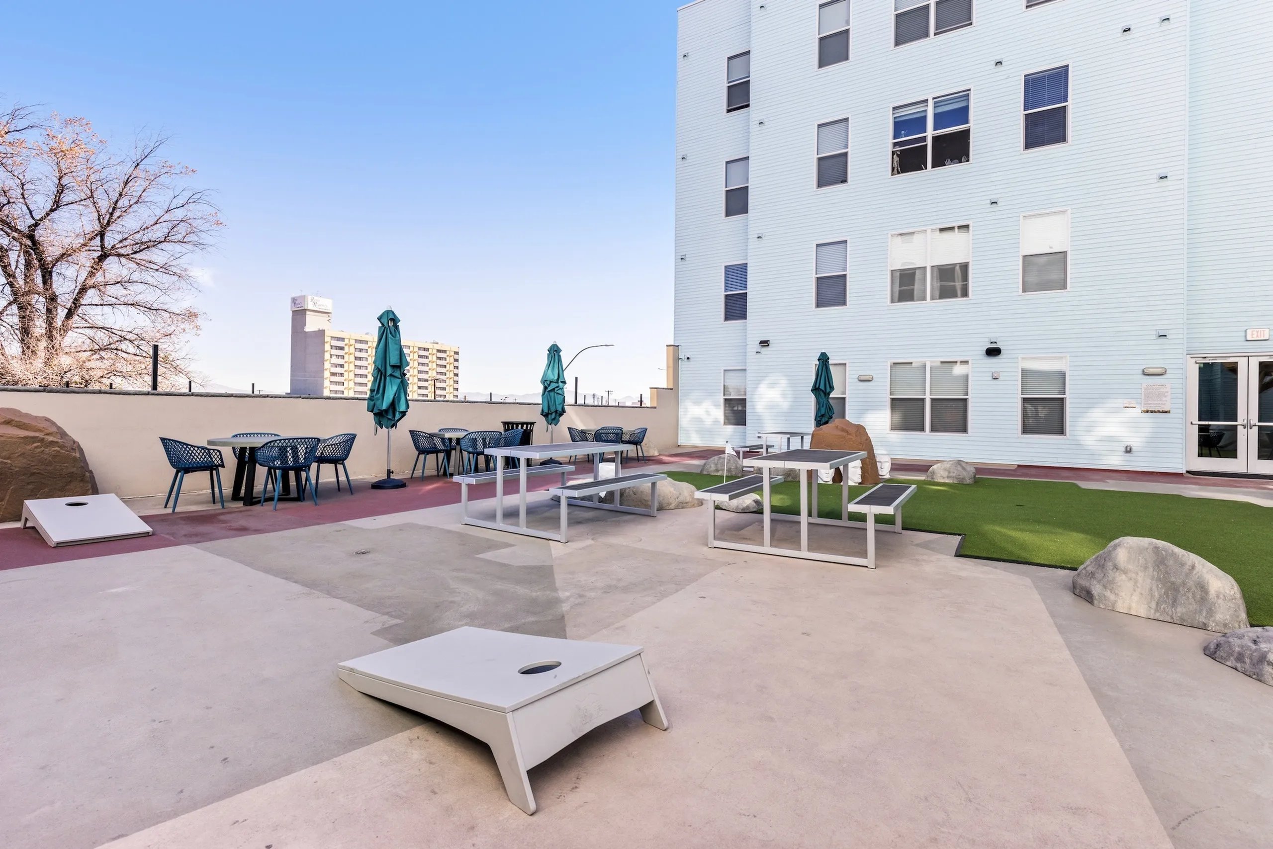 Picnic tables umbrellas chairs and cornhole exterior at Canyon Flats in Reno Student Accommodation