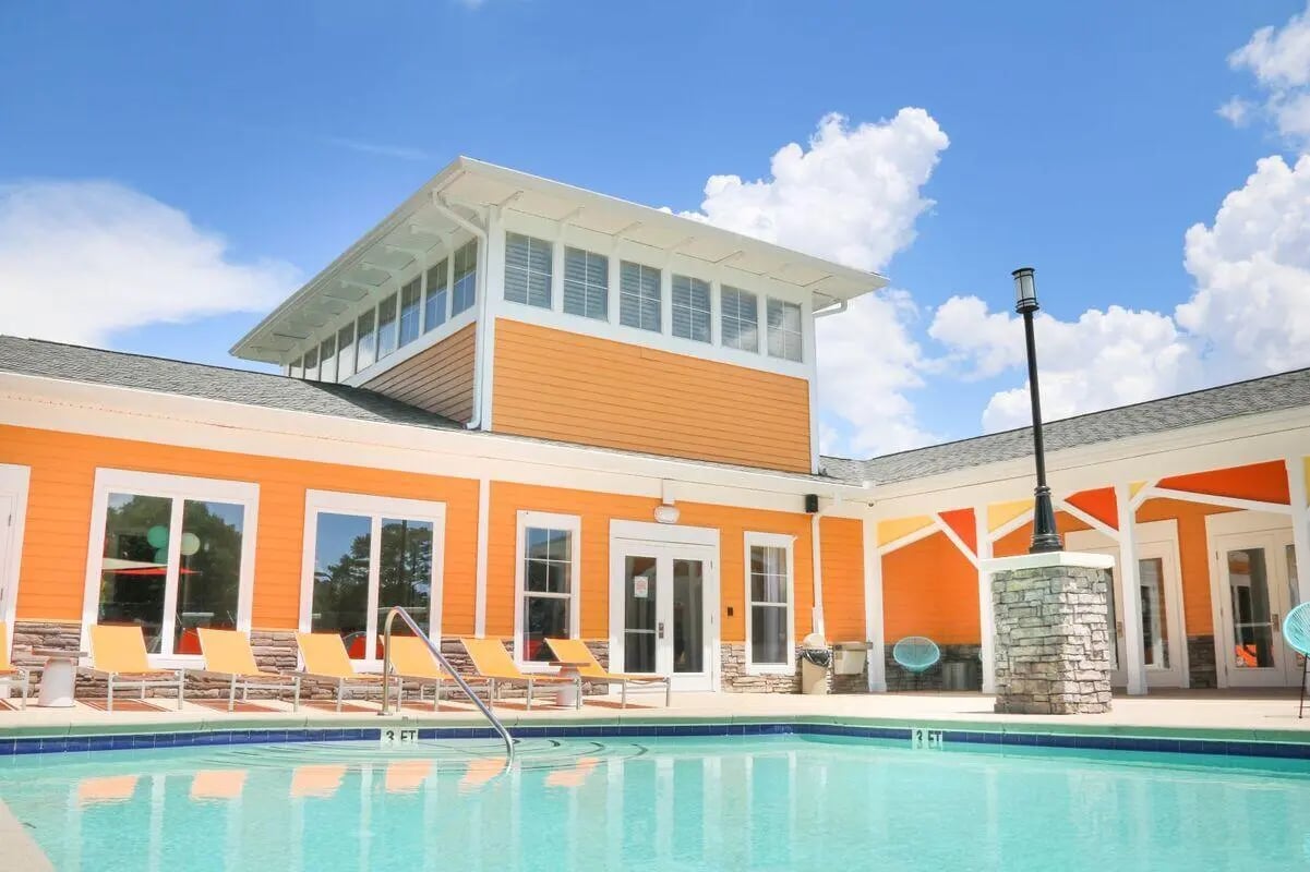 Pool with lounge chairs and orange building exterior pool area at Clemson Edge in Clemson Student Accommodation