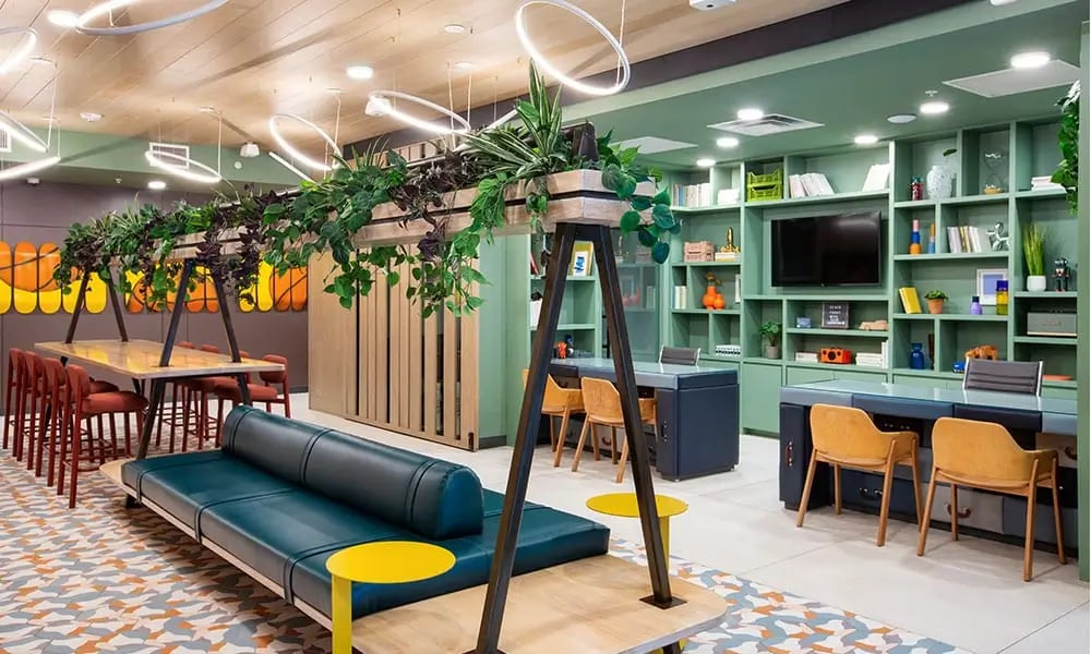 Green lounge with sofa tables and bookshelves common area at The Dean Campustown in Champaign Student Accommodation