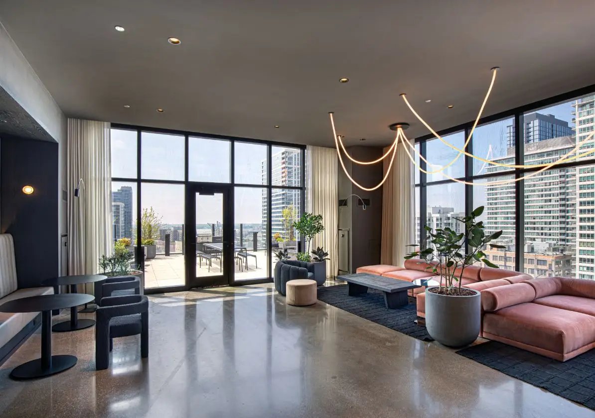 Pink sectional sofa plants concrete floor living room at Straits Row in Chicago Student Accommodation