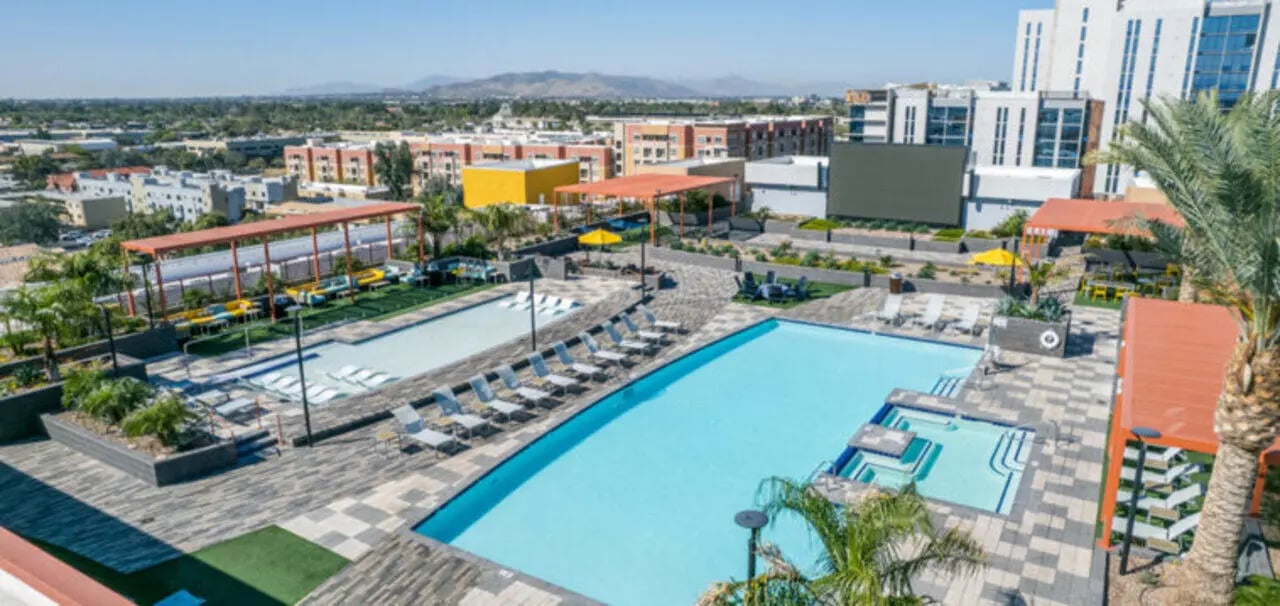 Pool area with lounge chairs and surrounding buildings exterior at Apollo Tempe in Tempe Student Accommodation