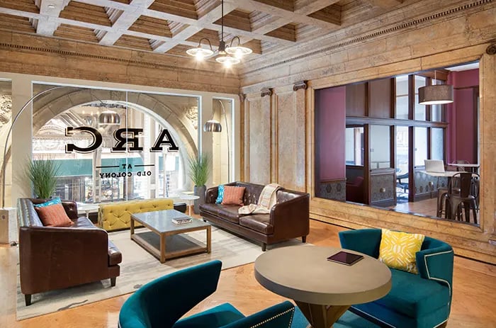 Lounge with brown sofas yellow bench living room at Arc at Old Colony in Chicago Student Accommodation