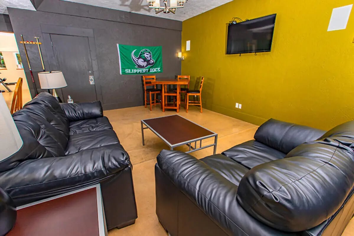 Black leather couches table dining area and flag living room at Campus Side in Slippery Rock Student Accommodation