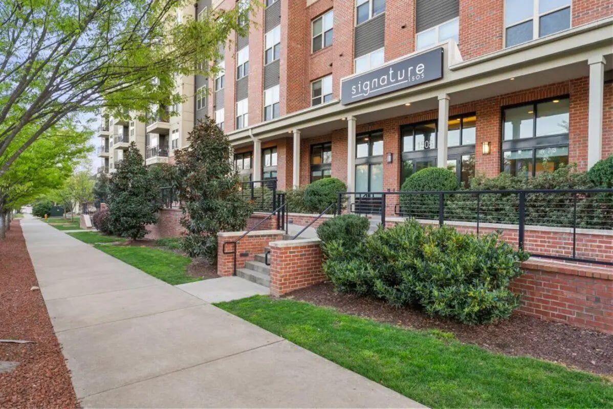 Brick building with trees and sidewalk exterior at Signature 1505 in Raleigh Student Accommodation