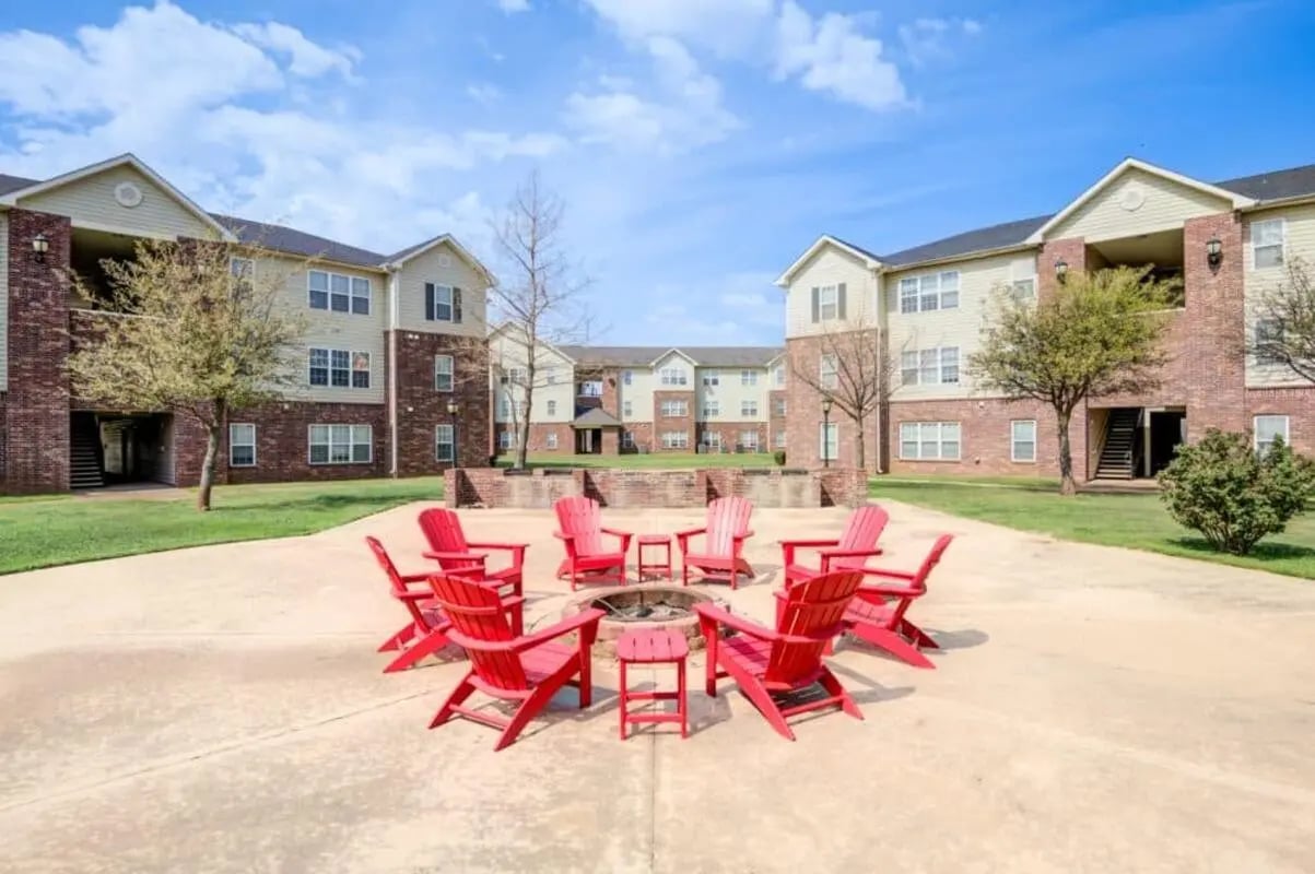 Red Adirondack chairs surrounding fire pit exterior at Mustang Village in Wichita Falls Student Accommodation