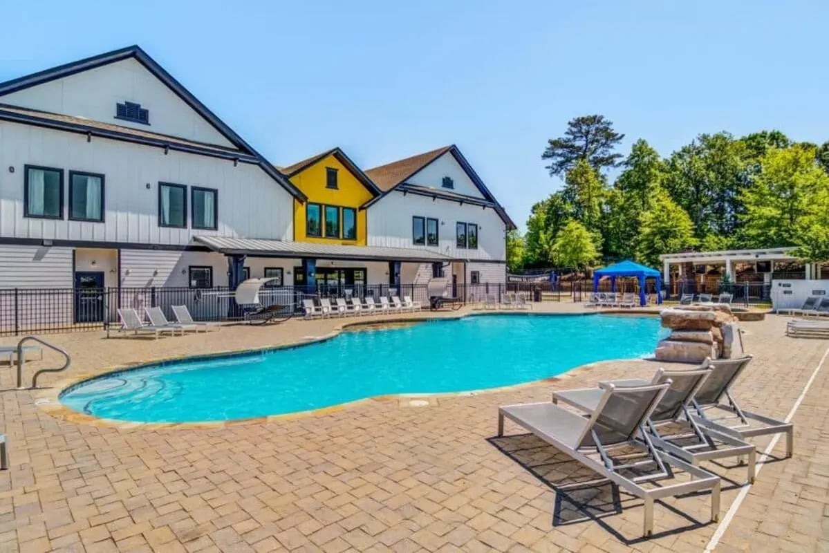 Pool with lounge chairs and buildings exterior at The Collective At Auburn in Auburn Student Accommodation