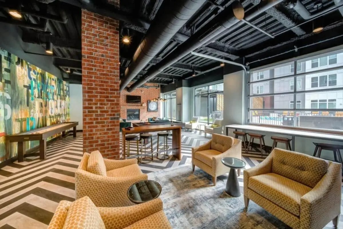 Sofa chairs shuffleboard table fireplace common area at Proximity At 10th in Greenville Student Accommodation
