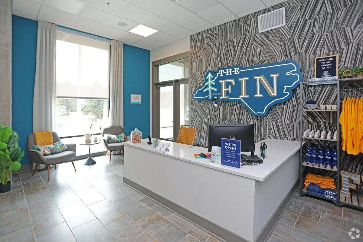 Reception desk with chairs and logo area. at The Finmore at 241 in Boone Student Accommodation
