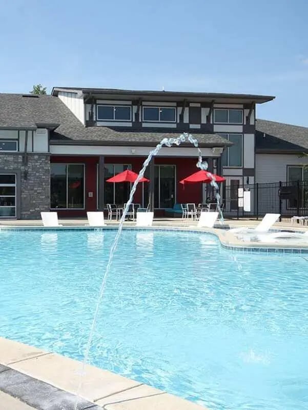 Pool with lounge chairs and red umbrellas exterior at Lark in the Woods in Tuscaloosa Student Accommodation