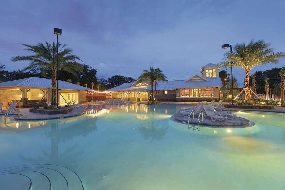 Pool with lounge chairs and palm trees exterior at Redpoint Tallahassee in Tallahassee Student Accommodation