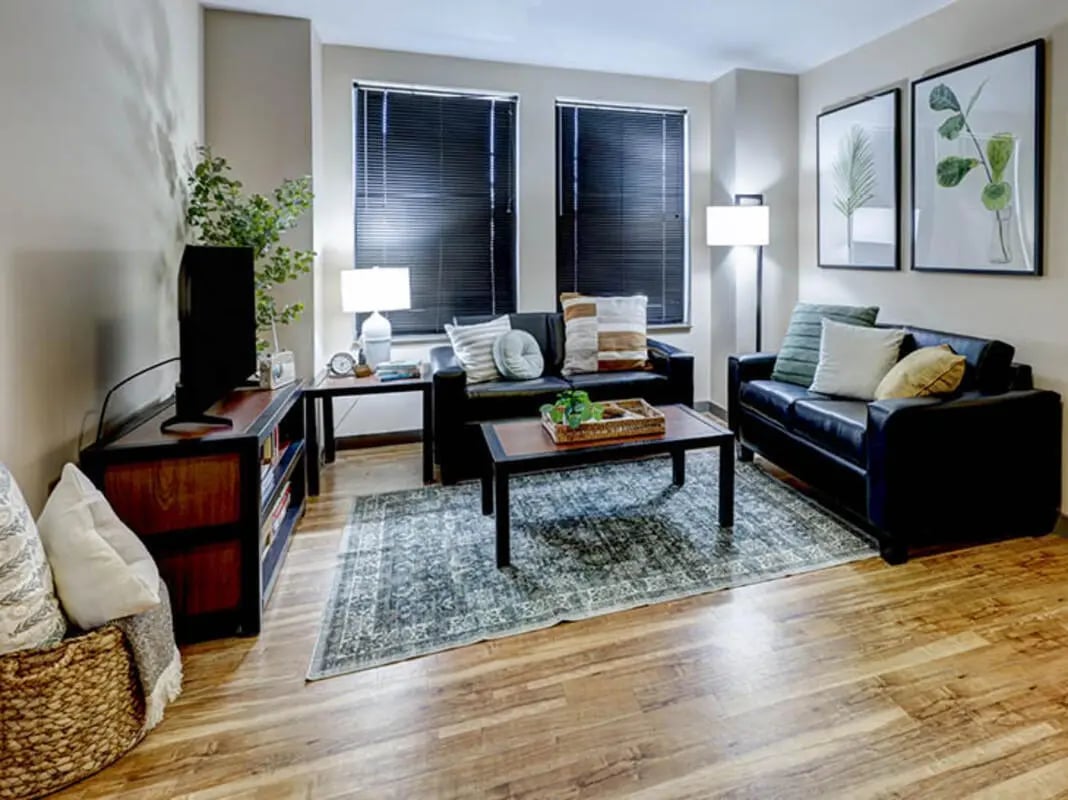 Black leather sofas coffee table rug living room at 1200 West Marshall in Richmond Student Accommodation