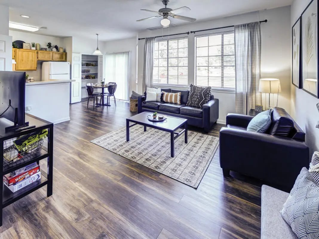 Dark sofas coffee table dining area kitchen living room at Bishops Square in San Marcos Student Accommodation