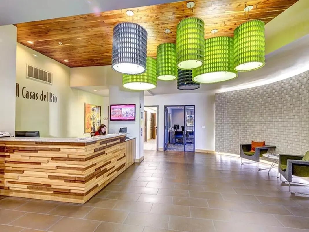 Reception desk with wood planks and green lamps Lobby at Casas del Rio in Albuquerque Student Accommodation