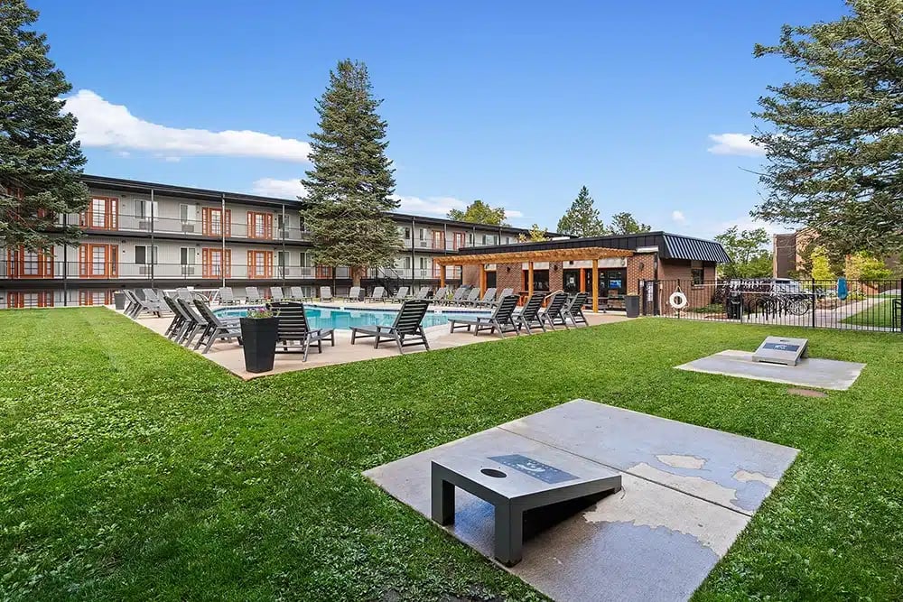 Cornhole game by pool with lounge chairs exterior at The Lodge