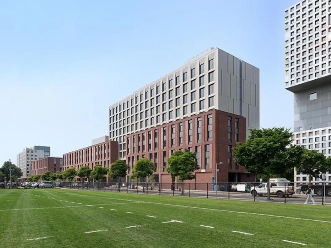Modern brick and concrete buildings with grassy field exterior at Graduate Junction in Cambridge Student Accommodation