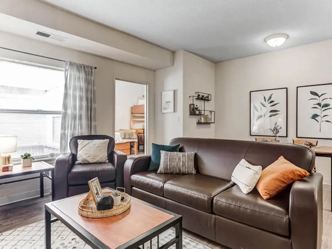 Brown leather sofa armchair coffee table living room at GrandMarc Seven Corners in Minneapolis Student Accommodation