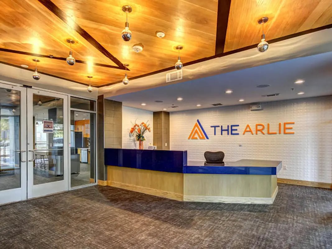 Reception desk with logo and seating area exterior at The Arlie in Arlington Student Accommodation