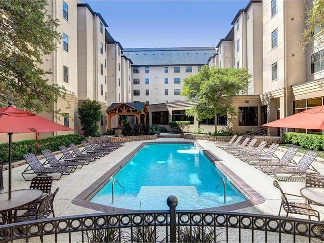 Pool lounge chairs umbrellas and outdoor seating area exterior at The Callaway House in College Station Student Accommodation