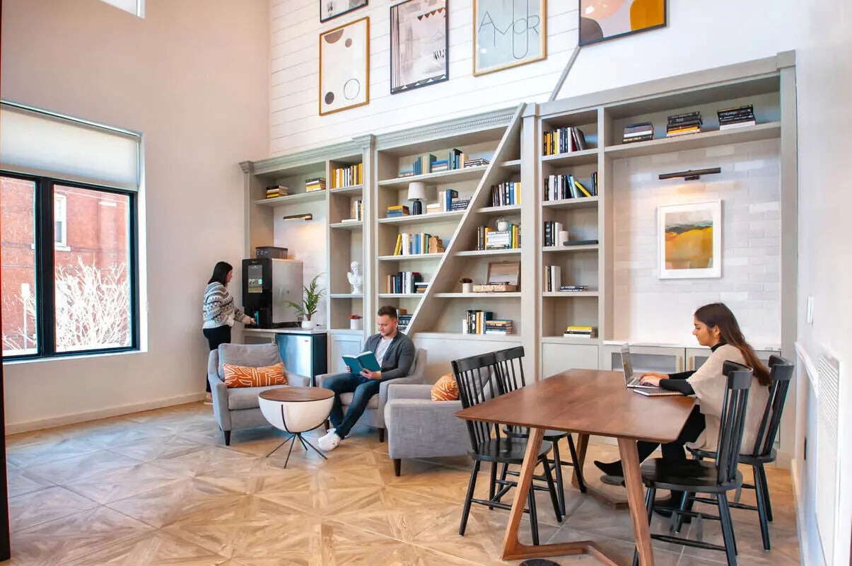 People in lounge with bookshelves and seating area at Paloma University City in Philadelphia Student Accommodation