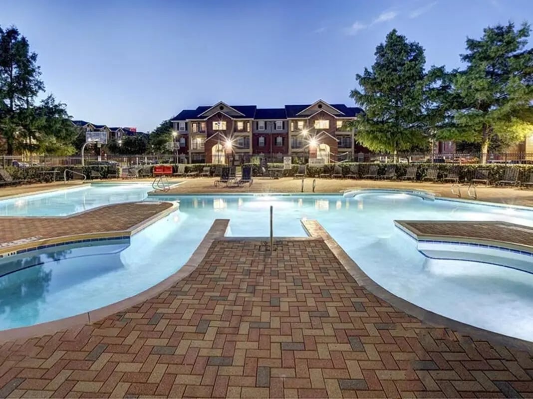 Pool with lounge chairs building exterior at University Trails in Lubbock Student Accommodation