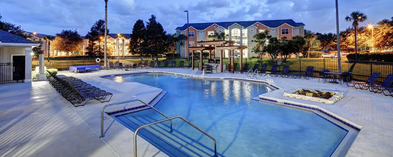 Blue swimming pool lounge chairs tables exterior at The Village At Science Drive in Orlando Student Accommodation