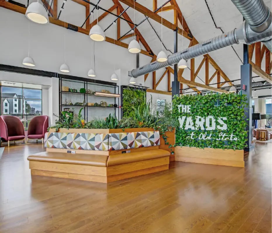 Modern seating area with plants and logo living room at The Yards at Old State in State College Student Accommodation