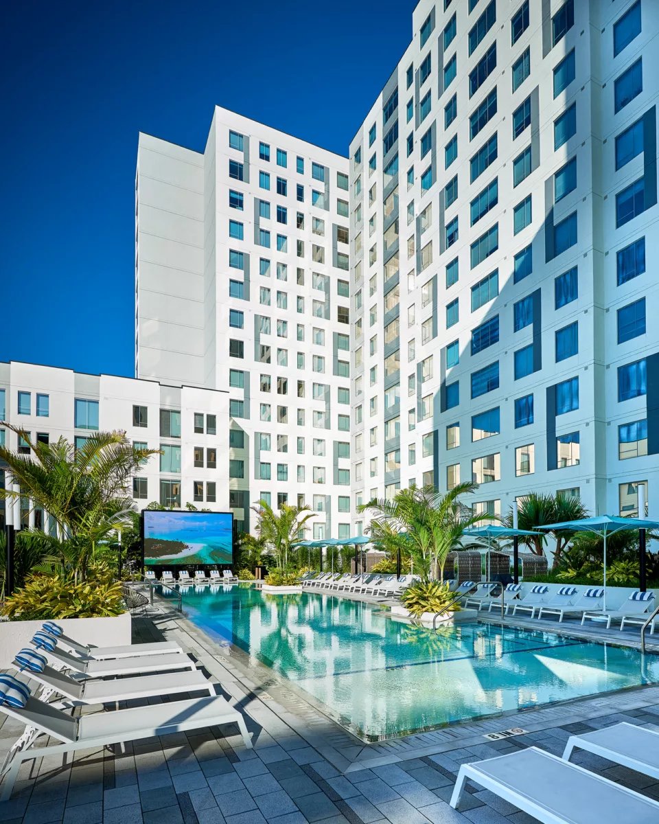 Modern building pool lounge chairs palm trees exterior at Lapis in Miami Student Accommodation