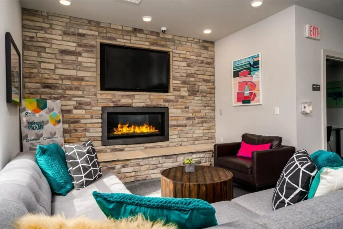 Sofa fireplace TV artwork brown chair living room at The Rocks in East Lansing Student Accommodation