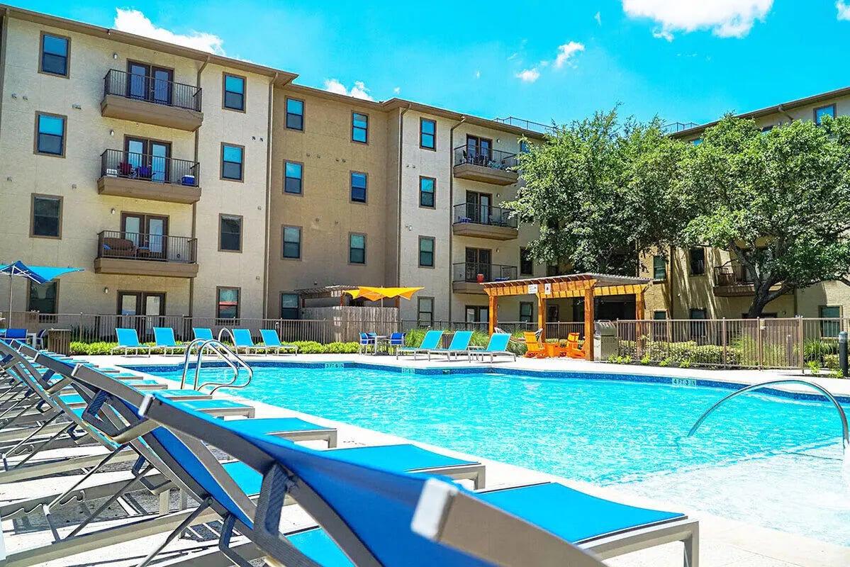 Apartment building pool lounge chairs exterior at Prado Student Living in San Antonio Student Accommodation