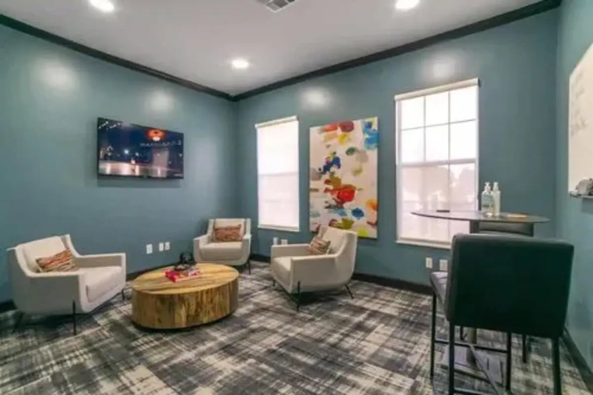 Three armchairs coffee table and television living room at Arden Villas in Orlando Student Accommodation