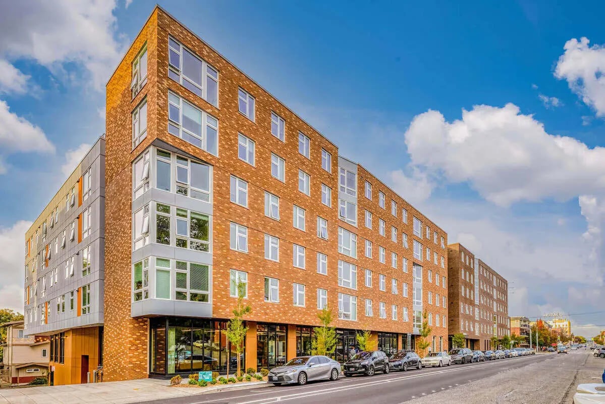 Modern brick apartment building with cars parked exterior at Stateside in Bellingham Student Accommodation
