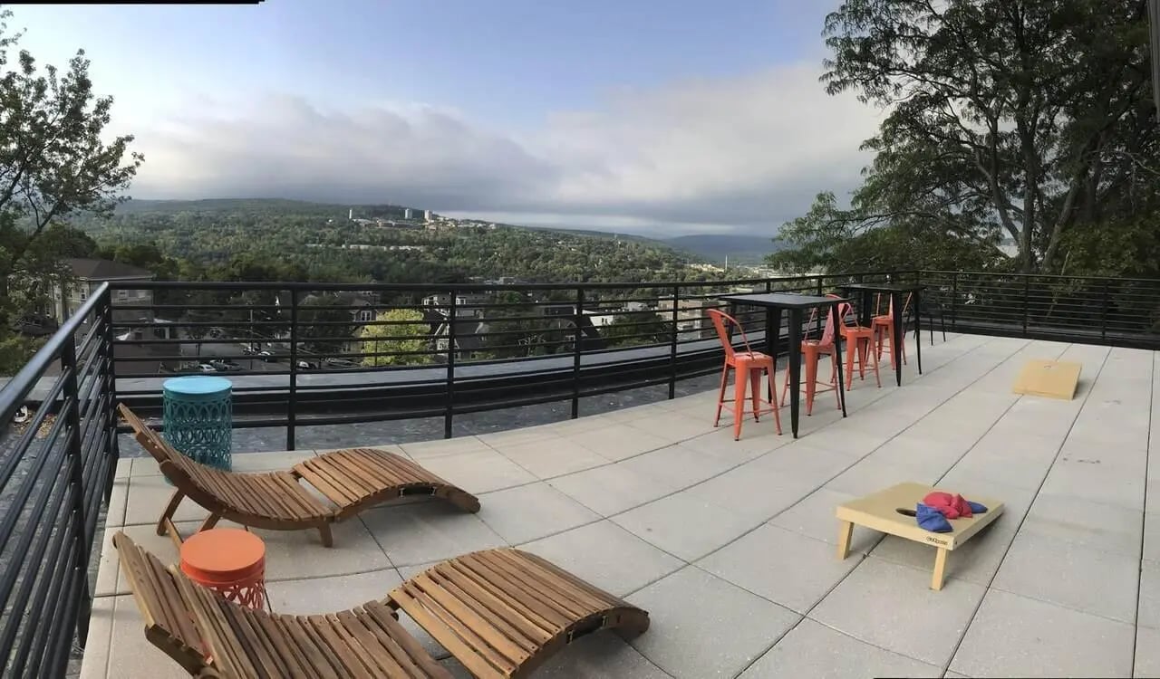 Deck chairs tables chairs and cornhole game exterior at The Lux Apartments Ithaca in Ithaca Student Accommodation