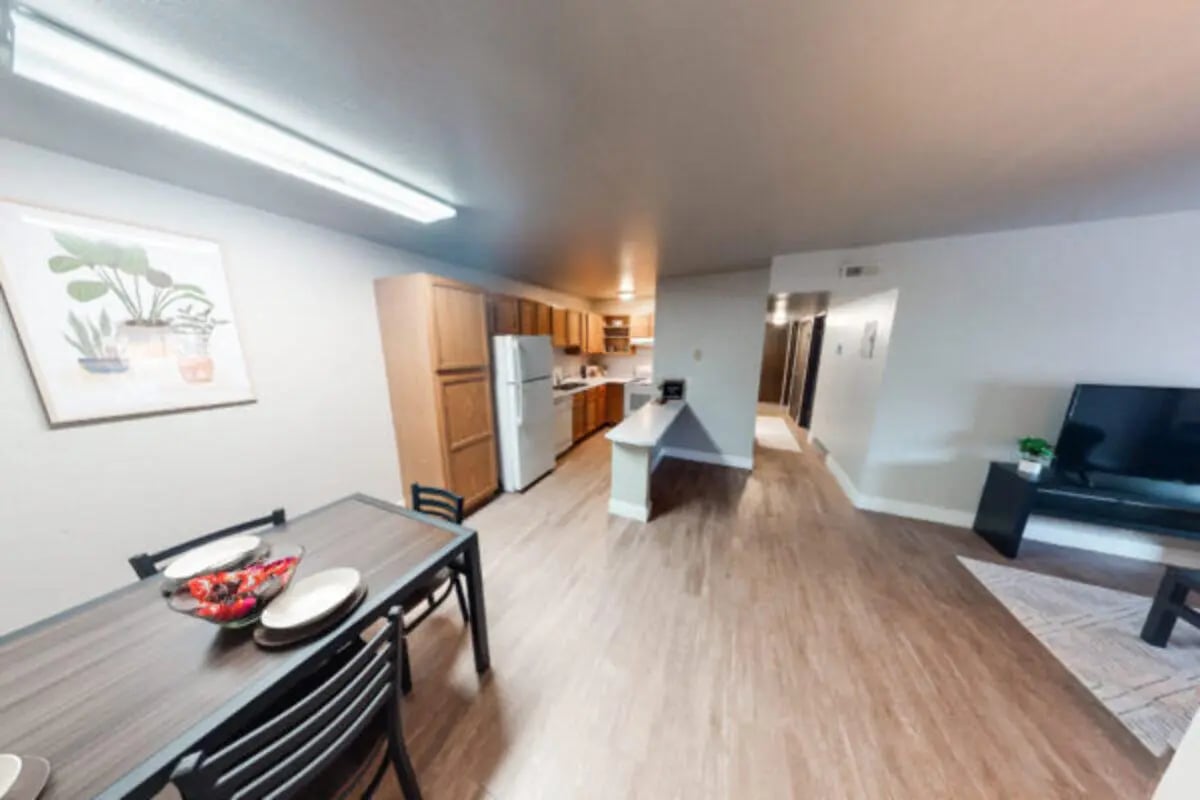 Dining table kitchen cabinets refrigerator and television living room at Centennial Apartments in Provo Student Accommodation