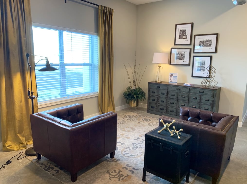 Two brown armchairs dark chest lamp console table living room at Eight Thirty Water Tower Apartments in Big Rapids Student Accommodation